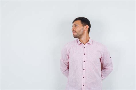 Giovane maschio che guarda lontano con le mani sulla schiena in camicia ...