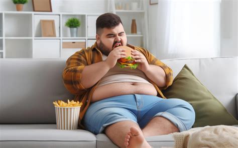 AI generated Fat man sitting and eating hamburger on the sofa. in the ...