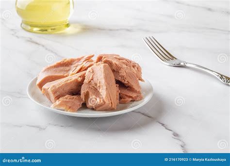Canned Tuna Fillet Pieces On A White Saucer And Fork Over Marble Table ...