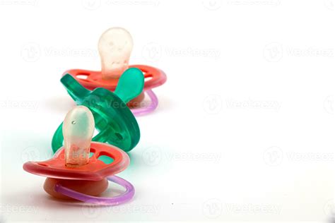 Two pink pacifiers and one turquoise pacifier for newborn on white ...