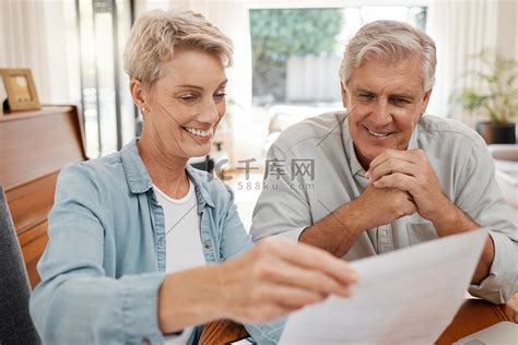 幸福的夫妻，坐在家里阅读和文书工作或账单、抵押贷款或退休计划或支出的文件。高清摄影大图-千库网
