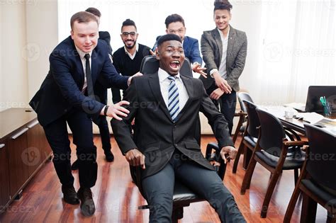 Six multiracial business mans standing at office and roll man on chair ...
