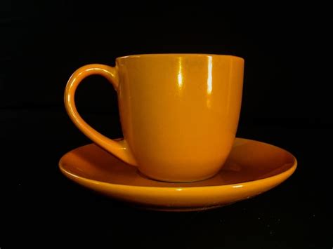 Yellow cup and saucer against black background | Premium Photo