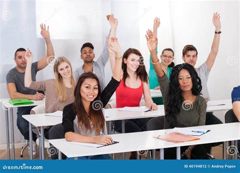 College Students Raising Hands In Classroom Stock Photo - Image: 40194812