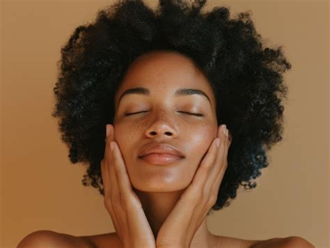 A portrait of an woman with closed eyes gently touching her face and ...