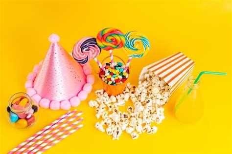 A top view popcorn and candies along with pink funny cap and cocktail ...