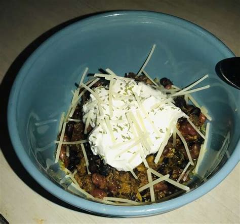 A bowl of Laura's quick slow cooker turkey chili, topped with shredded cheese, sliced green onions,