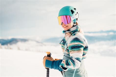 Kobieta w stroju narciarskim z kaskiem i goglami narciarskimi na głowie ...