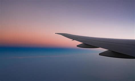 Wing of plane with beautiful sunrise skyline. Airplane flying on blue ...