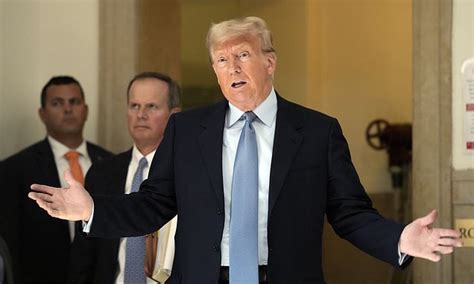 US President Donald Trump, wearing a dark blue suit, white shirt, and light blue tie, looks ahead, h