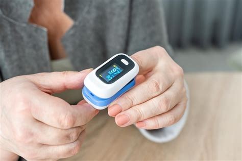 Pulse oxymeter on a woman finger hand on a wooden table. top view ...