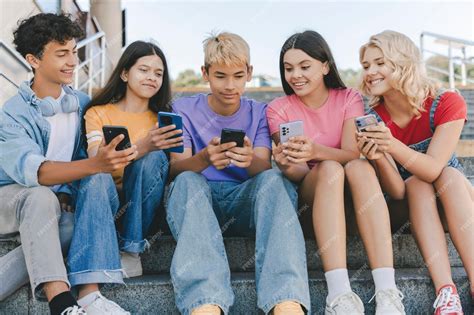 Premium Photo | Group of smiling friends teenagers holding mobile ...