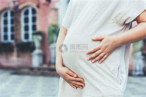 孕妇在照顾孩子的同时在家感到快乐年轻的准妈抱着婴儿在怀孕的肚子里产前护理和高清图片下载-正版图片506253094-摄图网