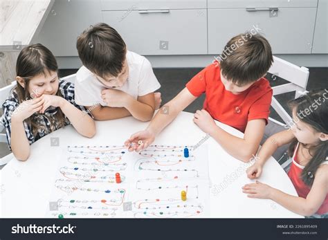 4件の「Happy little school friends play board game on paper map with dice ...