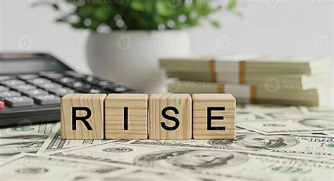 Wooden blocks spelling RISE on a bed of US currency suggesting ...