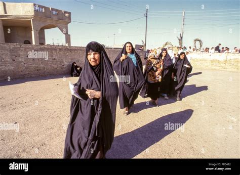 Black-and-white photo of Saddam Hussein, in a suit, with a group of women students
