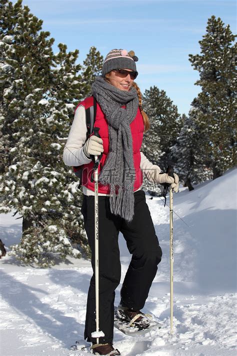 穿着雪鞋在雪地里行走的女人高清摄影大图-千库网
