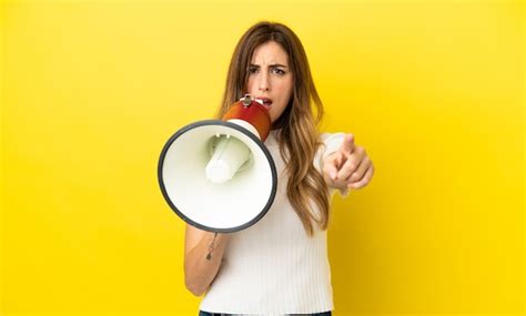 Caucasian woman isolated on yellow background shouting through a ...