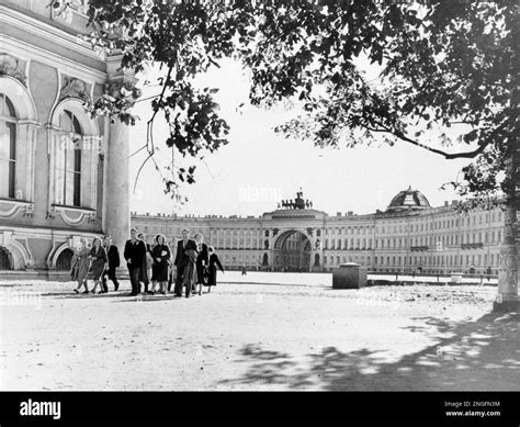 A group of people pass the State Hermitage Museum, left, housed in the ...