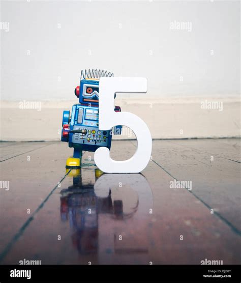 number 5 robot toy on a woden floor with reflection Stock Photo - Alamy
