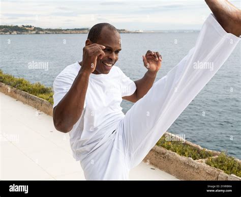 Brazilian man practicing capoeira martial arts kick near a scenic ...