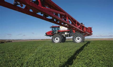 A large red Case IH agricultural sprayer with an extended boom ...