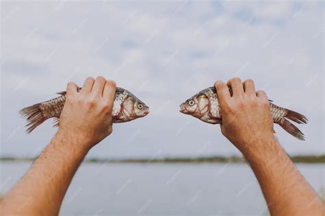 Premium Photo | Close up a man holds in his hands two fish with open ...