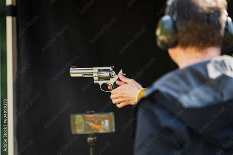 Shooting from a revolver in a shooting range outdoors. Stock Photo | Adobe Stock