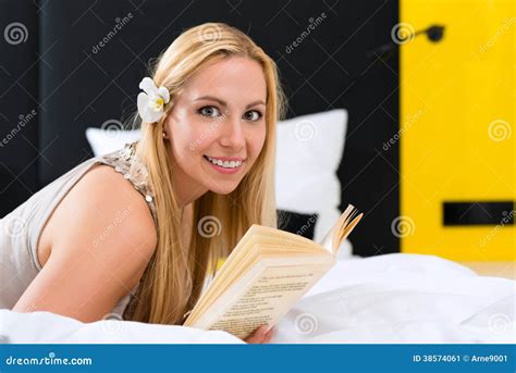 Woman reading in The Ritz-Carlton bed at a hotel