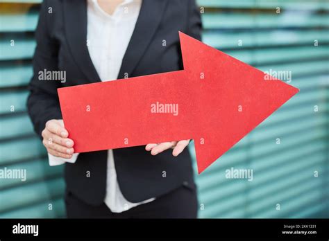 Businesswoman holding big red arrow symbol sign to the right in front ...