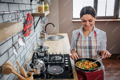 Cheerful nice woman stand in kitchen at stove | Premium Photo