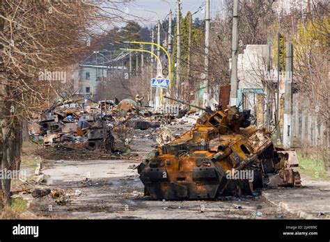 A man walks past a burnt armoured personnel carrier near buildings destroyed in the course of Ukrain
