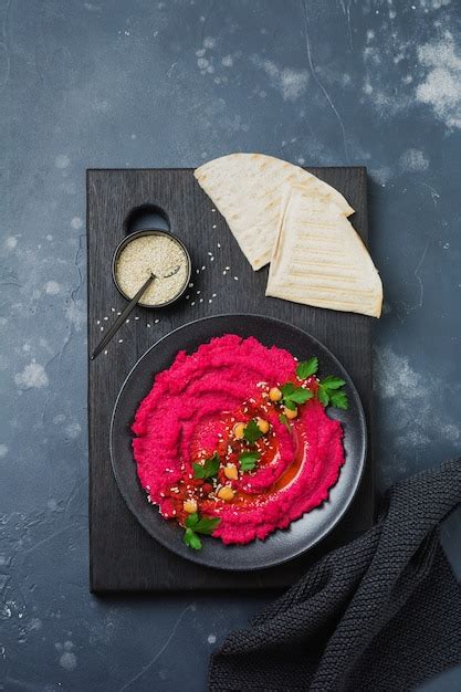 Homemade beetroot hummus in black ceramic dish on old dark concrete ...