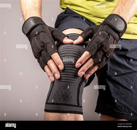 Athlete bodybuilder wearing knee support brace, elastic kneecap bandage, sleeve for compression ...