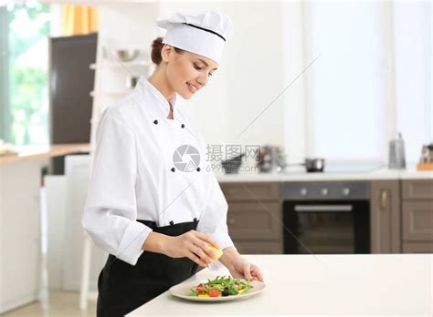 年轻女厨师在厨房里用柠檬汁调味沙拉高清图片下载-正版图片502773980-摄图网