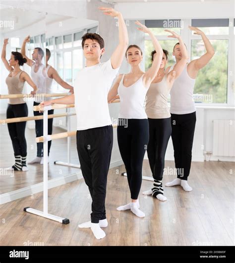 Guy performing third position at barre during group ballet class Stock ...