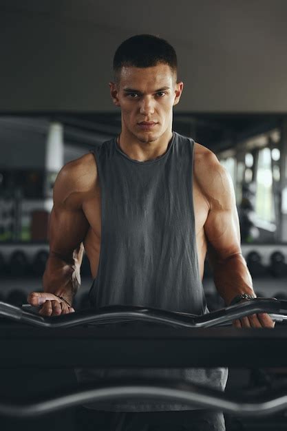 Vertical photo of muscular fitness man working out with heavy ez curl ...