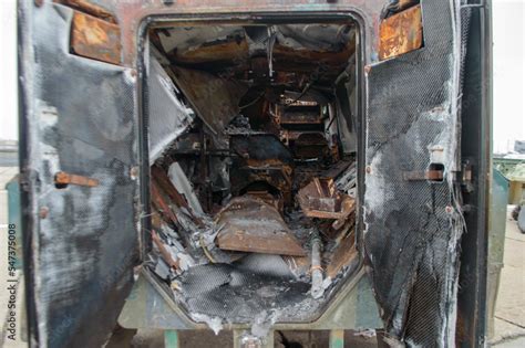 A man walks past a burnt armoured personnel carrier near buildings destroyed in the course of Ukrain