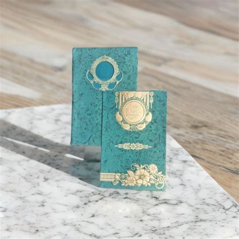 A green wedding card with a silver medallion on it | The Invota Wedding ...