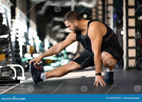 Handsome Young Man Performing Leg Stretch before Workout in Gym Stock Photo - Image of athlete ...