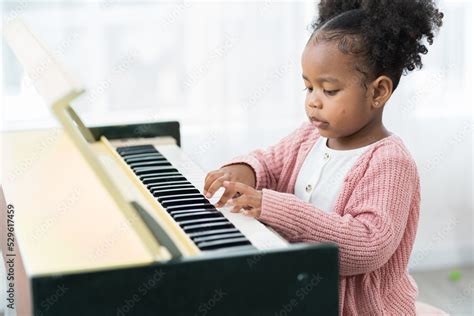 Child girl playing piano at home. African American little girl practice ...
