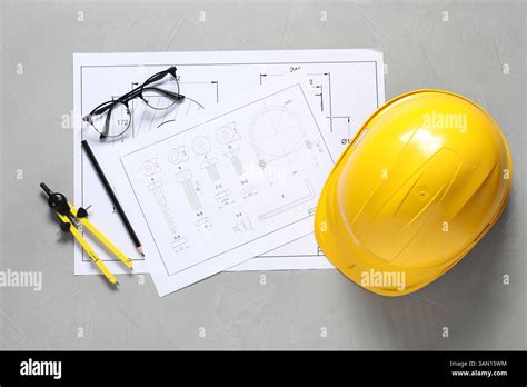 Different engineering drawings, hard hat, pencil, divider and glasses ...