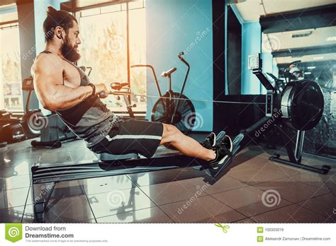 Muscular Fit Man Using Rowing Machine At Gym Stock Image - Image of ...