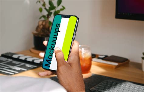 Hand holding iPhone 13 mockup - Mockuuups Studio