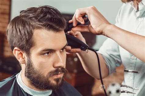 年轻的理发师在理发店里让发型有吸引力的男人的手照片-正版商用图片0s7ekb-摄图新视界