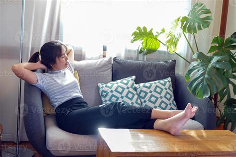 Asian woman lay down and relax on the sofa She propped her legs up ...