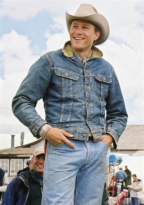 a man wearing a cowboy hat and jeans standing in front of a group of people