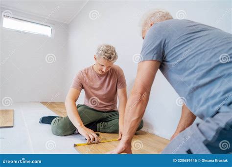 Father and Adult Son Installing Flooring in New Home by Their Own ...