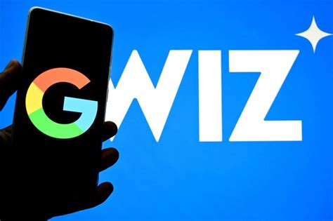 A phone displaying a Google logo is held up to a screen displaying a Wiz logo