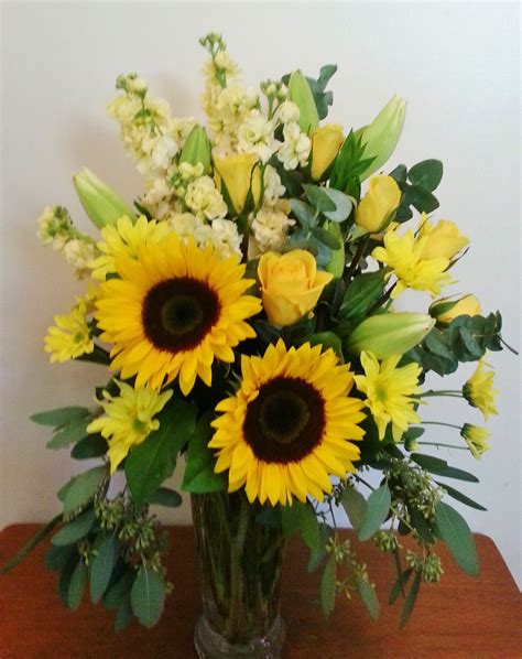 An all yellow arrangement that includes yellow roses and sunflowers ...